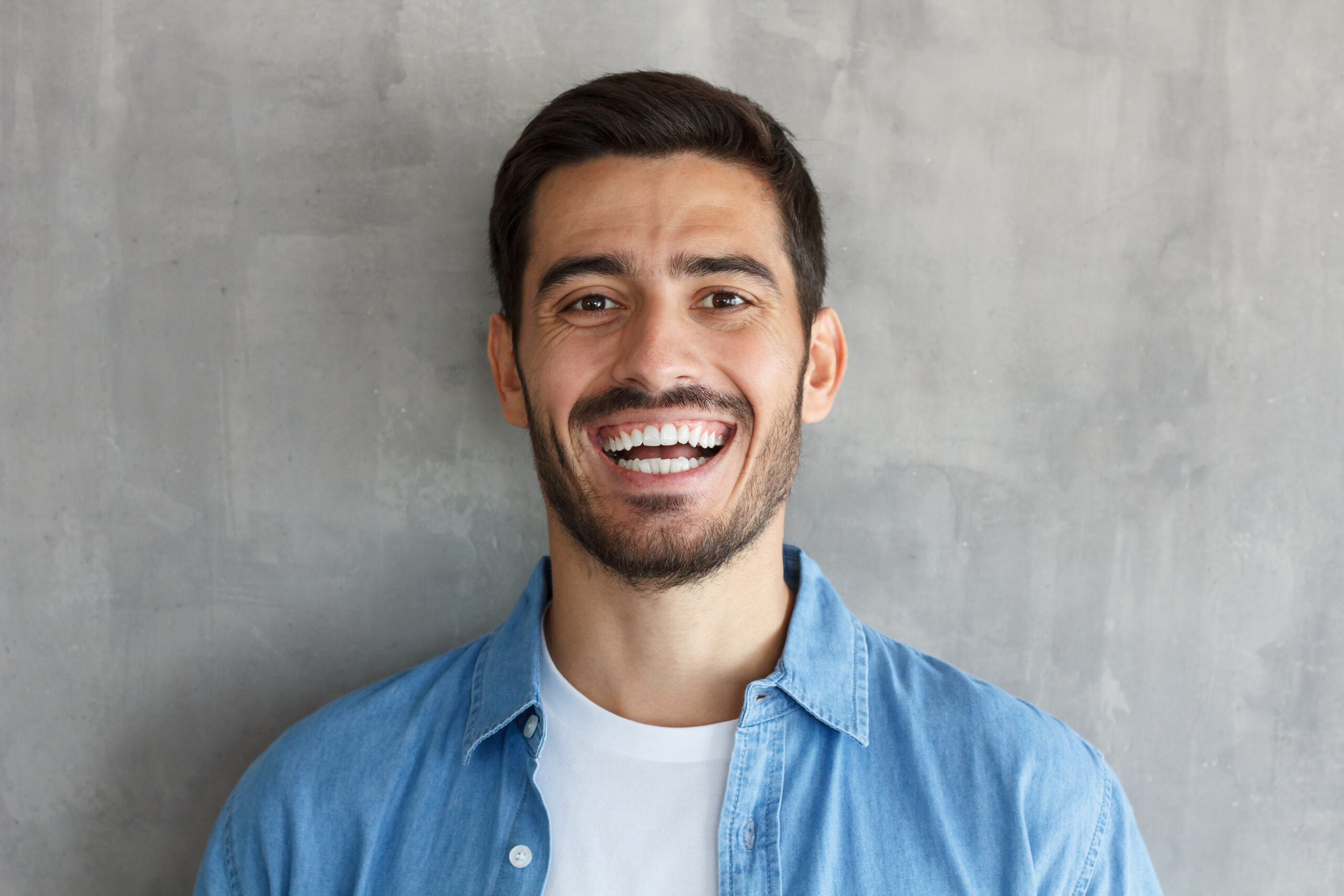 Joyful modern man smiles broadly, shows white perfect teeth. Positive emotions, happiness concept